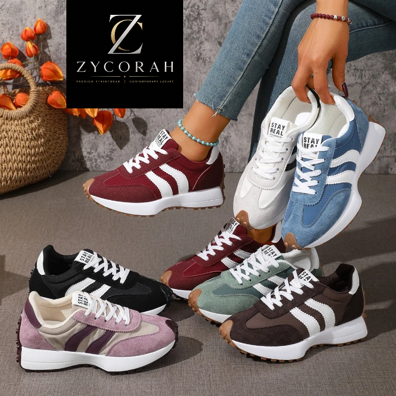 A lifestyle product shot of ZYCORAH sneakers in multiple colorways, featuring a model's hand holding a blue and white sneaker, with other colorways (burgundy, black, green, brown, pink) arranged on the floor. A woven basket with orange flowers and the ZYCORAH brand logo are visible in the background.