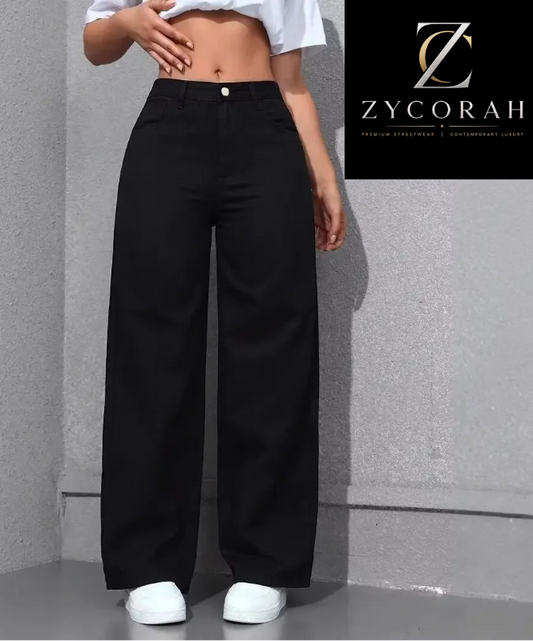 A model wearing black wide-leg pants with a white cropped top and white sneakers, standing against a textured gray wall. A black brand label for ZYCORAH is visible in the top right corner.