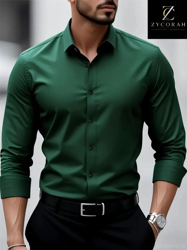 A man wearing a fitted long-sleeve button-up dress shirt in deep forest green, paired with black trousers and a black belt. The ZYCORAH brand logo is visible in the top right corner.