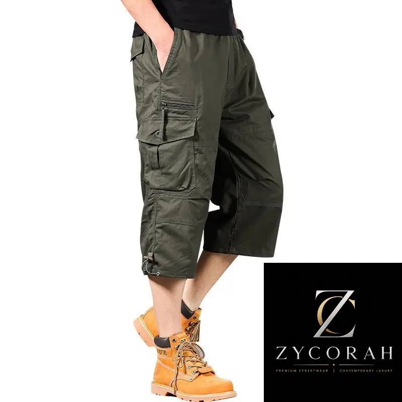 A person wearing olive green cargo shorts with multiple flap pockets and zippered details, paired with a black top and orange work boots, shown against a white background with a Zycorah brand logo in the bottom right corner.