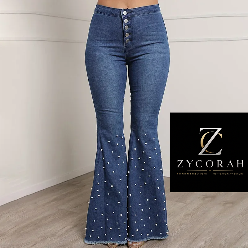A model is wearing blue denim flare jeans with white polka dots and a button fly, standing in a room with a light-colored wall and wood floor. A black brand overlay for Zycorah is on the right side of the image.