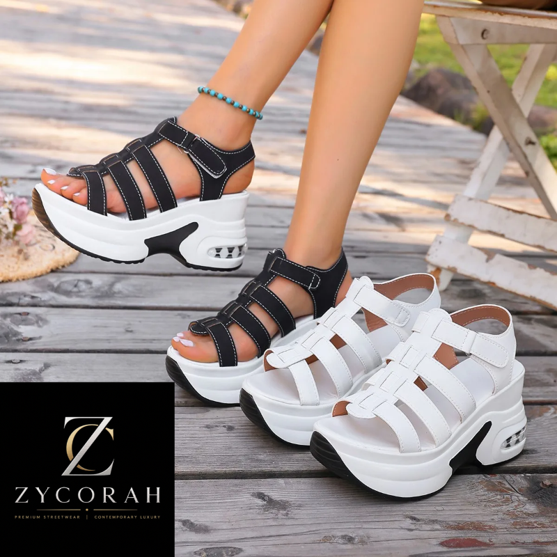 A pair of chunky platform sandals shown on a model's feet and as a pair on a wooden deck. One sandal is black and one is white, both featuring multiple cutout straps, a thick platform sole, and a hook-and-loop strap closure.
