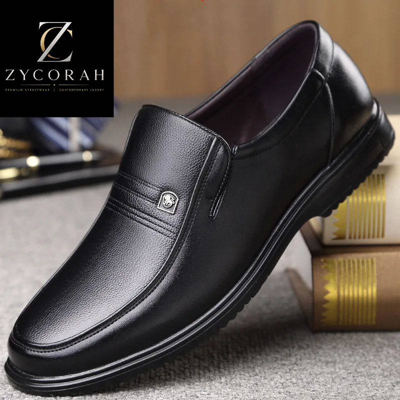 A black leather slip-on dress shoe shown at an angle on a textured gray surface with books in the background. The ZYCORAH brand logo is visible in the top-left corner.