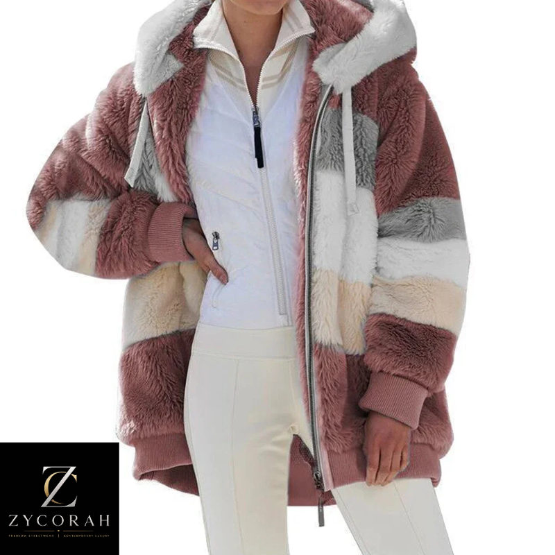 A woman models a chunky, oversized faux-fur zip-up jacket with horizontal color-blocked stripes in dusty rose, cream, white, and light gray. The jacket features a plush white faux-fur hood lining and ribbed cuffs.