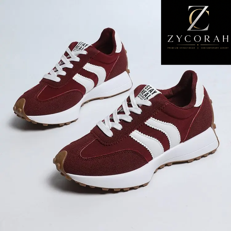A pair of ZYCORAH brand low-top sneakers in burgundy and white, featuring textured suede panels, white laces, and a chunky white midsole with a brown outsole, shown against a light gray background with a brand logo overlay in the top right.