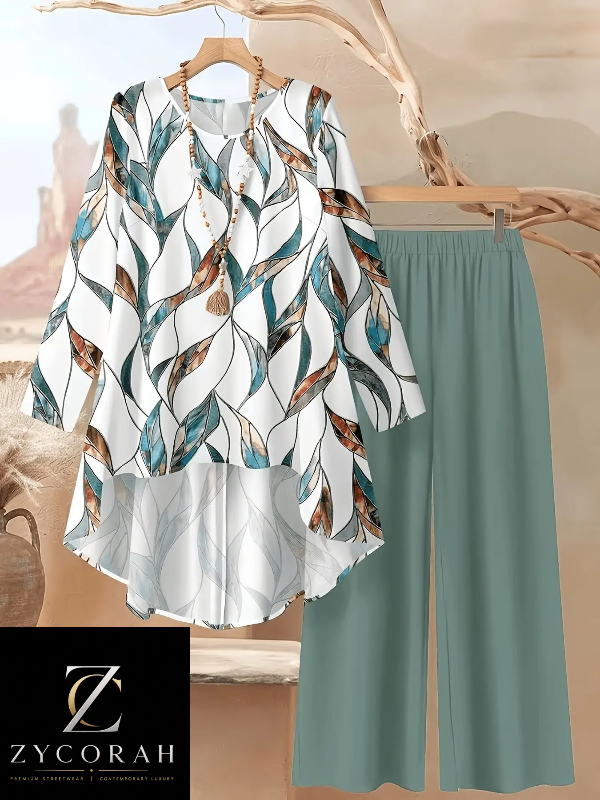 A women's two-piece outfit from ZYCORAH, featuring a white long-sleeve blouse with a teal and brown feather pattern, paired with sage green wide-leg pants, displayed on a wooden hanger and branch prop.