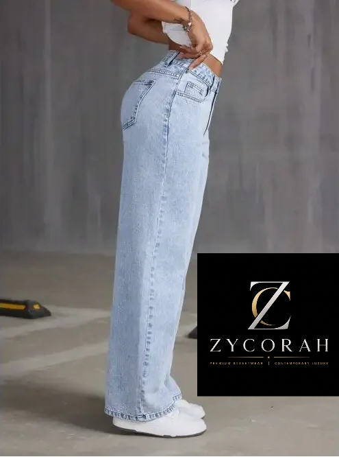 A model wearing light-wash wide-leg denim jeans and white sneakers, shown from the waist down in a studio setting. A black brand overlay for ZYCORAH is visible in the lower right corner.
