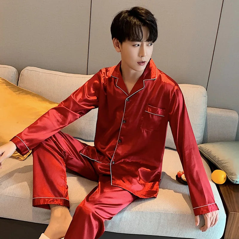Man wearing red satin pajamas sitting on a couch.