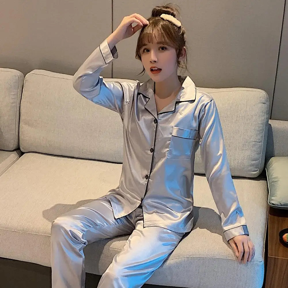 Woman wearing a light gray pajama set sitting on a gray couch.