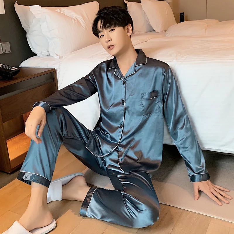 Person wearing blue satin pajamas sitting on the floor in a bedroom.