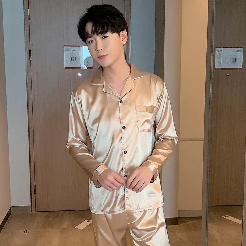 Man wearing a beige satin pajama set standing in a room with wooden doors.