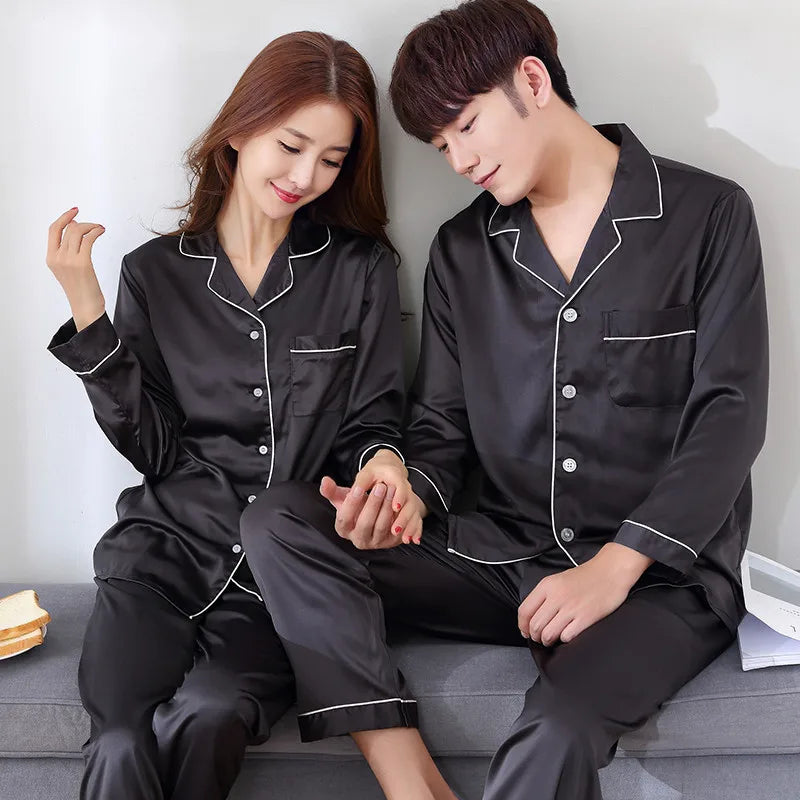 Two people wearing black satin pajamas sitting on a couch.