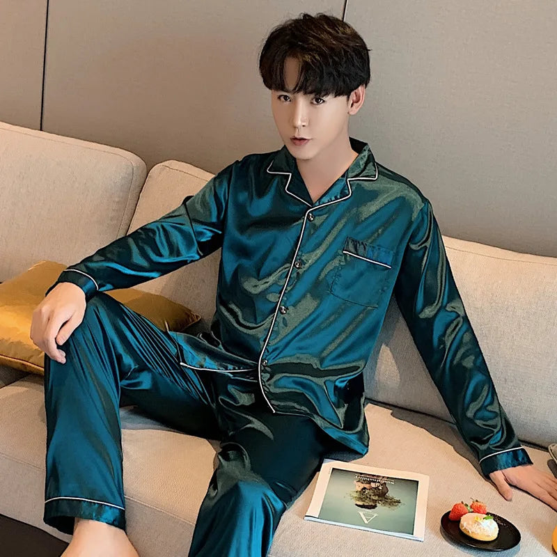 Man wearing teal satin pajamas sitting on a couch.