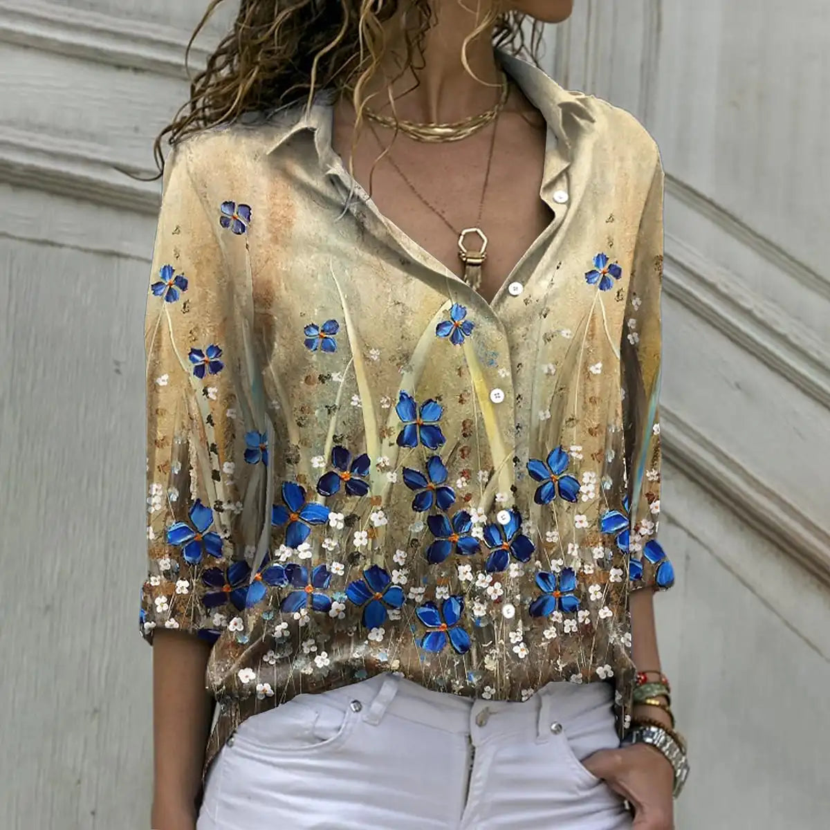 Woman wearing a blouse with floral embellishments against a neutral background