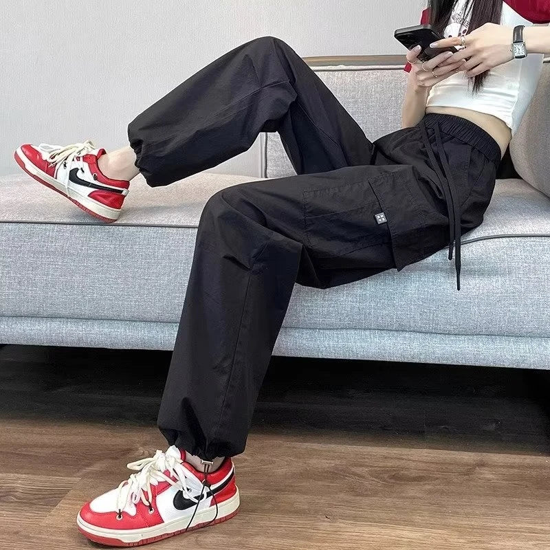 Person wearing black pants and red sneakers sitting on a couch.