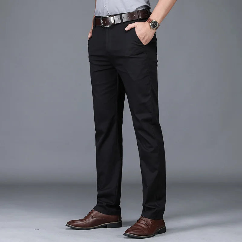 Person wearing black dress pants with brown shoes on a gray background