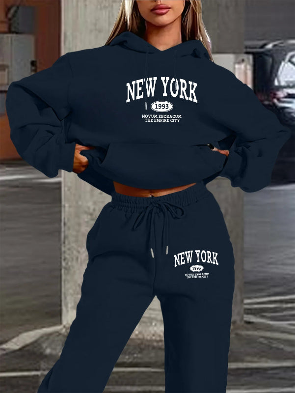Person wearing a navy blue 'New York' hoodie and sweatpants set with text on a blurred background.