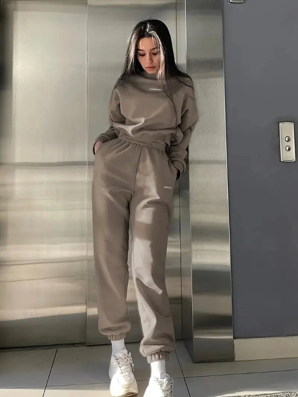 Person wearing a beige tracksuit standing in an elevator.