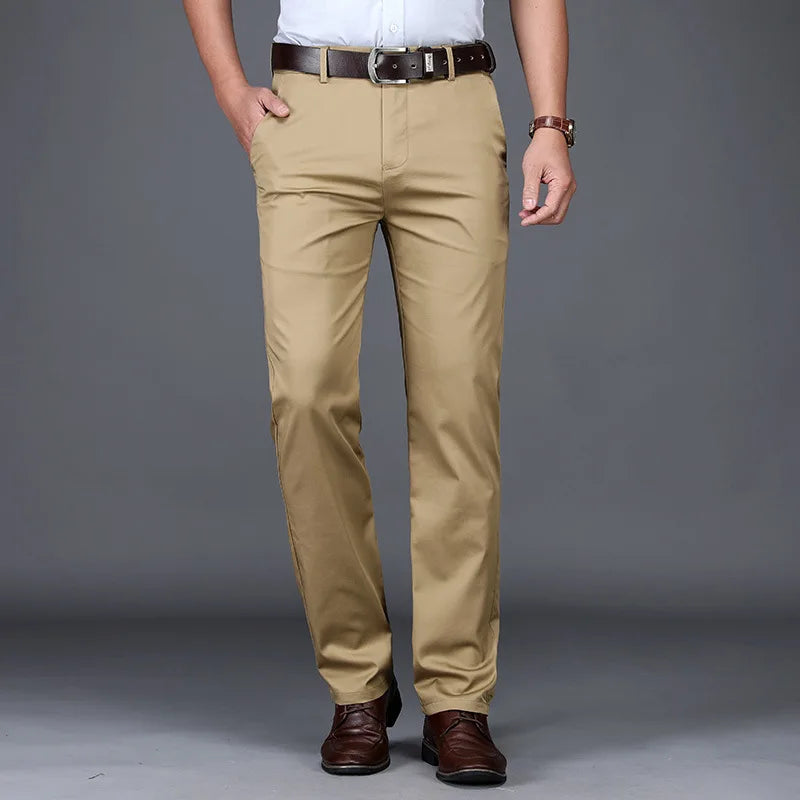 Person wearing beige pants with a belt and shoes on a gray background