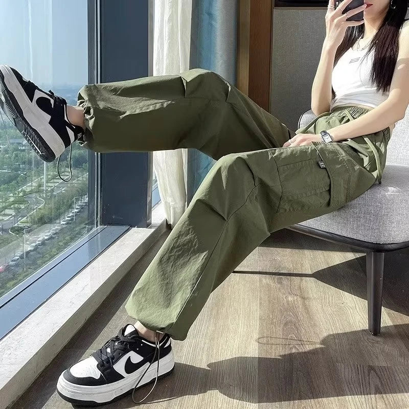 Person wearing green pants and black and white sneakers sitting by a window.
