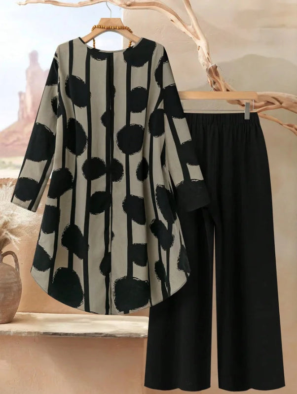 Black and white patterned cardigan with black pants on a wooden hanger against a neutral background
