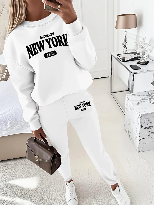 Person wearing a white 'Brooklyn New York 1955' sweatshirt and pants in a room.