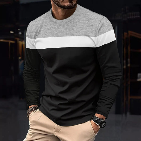 Man wearing a black and gray long-sleeve shirt with a blurred background