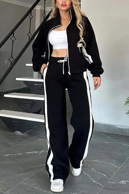 Person wearing a black and white tracksuit standing on a staircase.