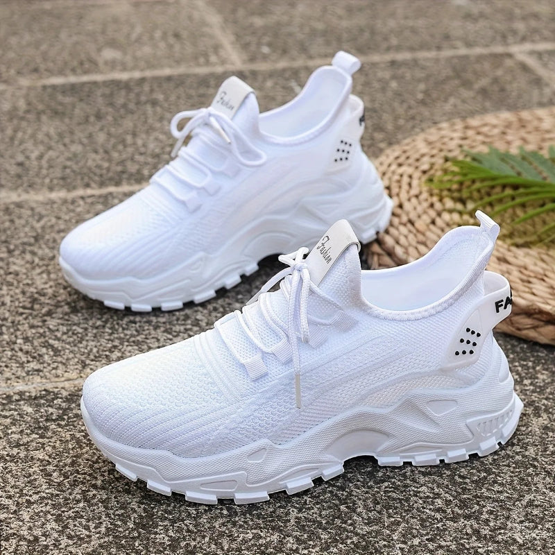 White athletic shoes on a textured surface with a woven mat and greenery in the background.