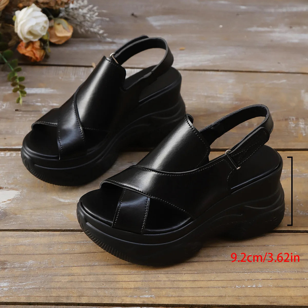 Black sandals on a wooden surface with measurement label