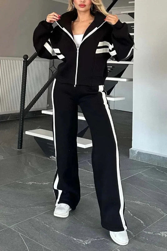 Person wearing a black tracksuit with white stripes indoors.