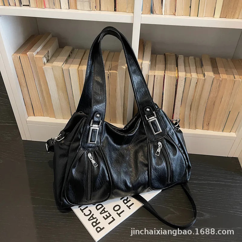 Black leather handbag on a dark surface with a bookshelf in the background