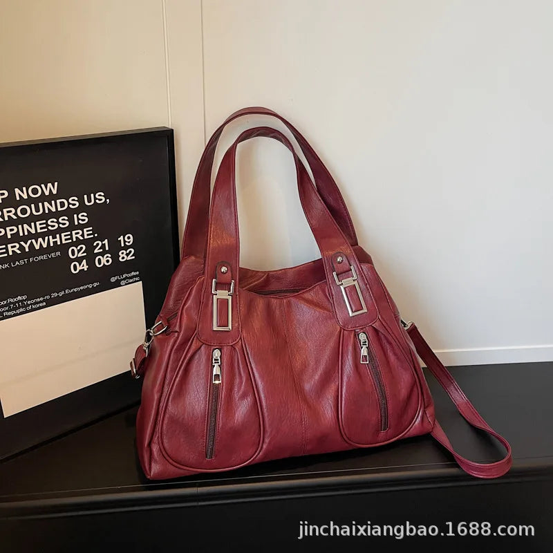 Red handbag on a dark surface with a light-colored wall in the background