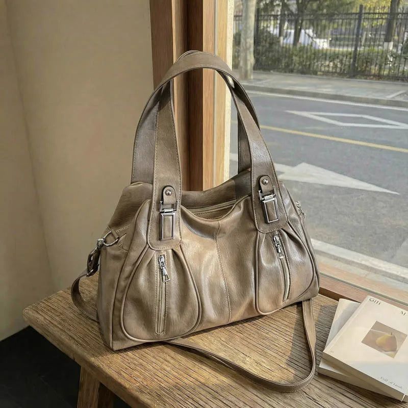Brown leather handbag on a wooden surface with a window in the background