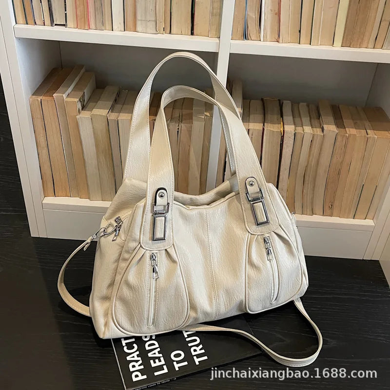 White handbag on a dark surface with a bookshelf in the background