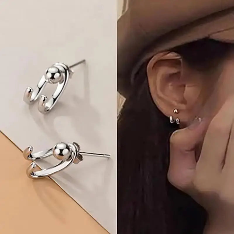 Silver hoop earrings displayed on a stand and worn by a person.