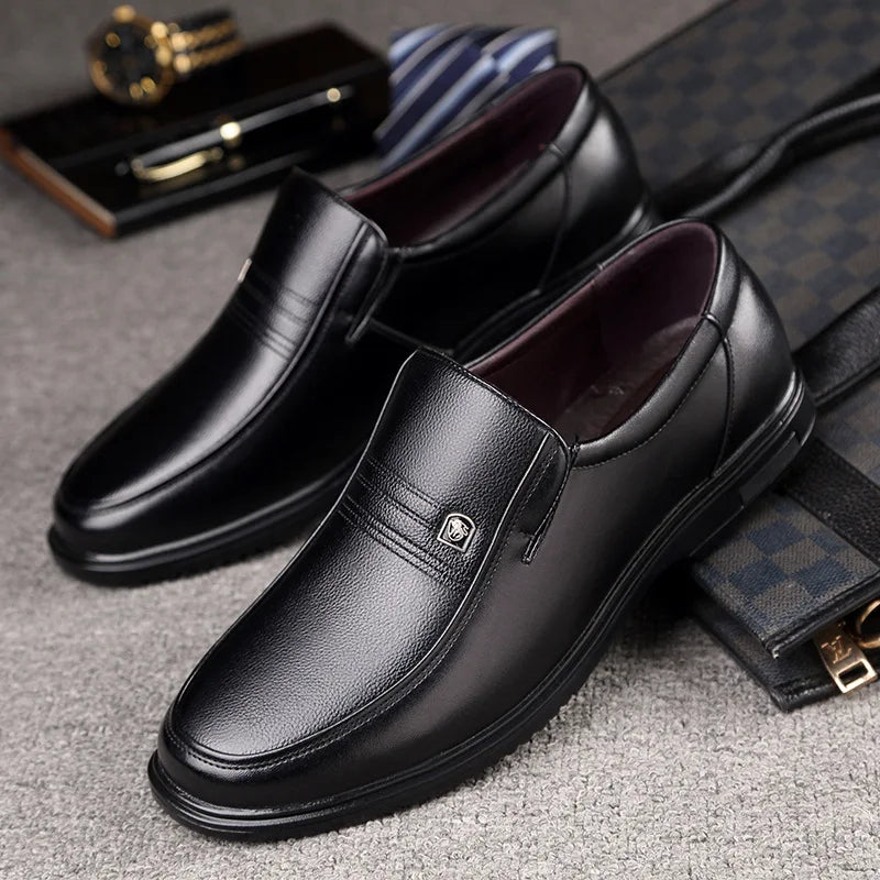 Black leather loafers on a textured surface with accessories in the background