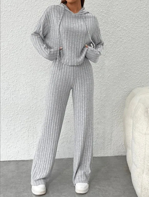 Person wearing a gray ribbed knit outfit with a matching hoodie and pants on a plain background.