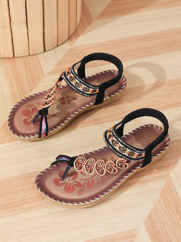 Pair of decorative sandals with floral patterns on a wooden floor.