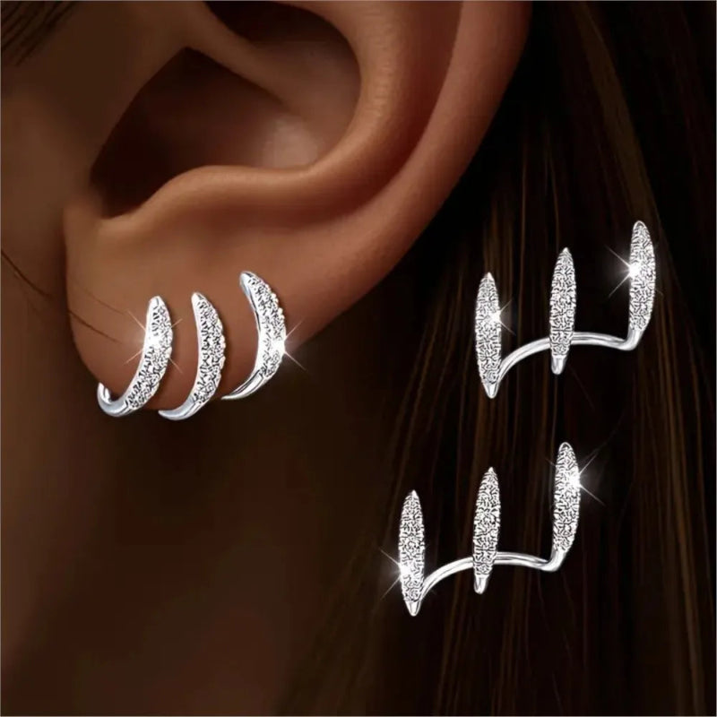 Silver ear cuff with gemstones worn on an ear against a dark background