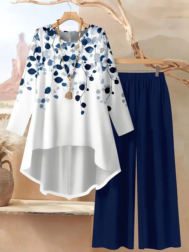 White blouse with blue floral pattern and navy pants on a wooden hanger.