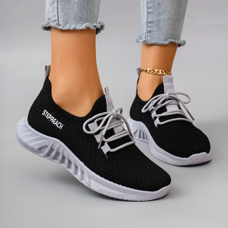 Black running shoes with white soles worn by a person on a gray background