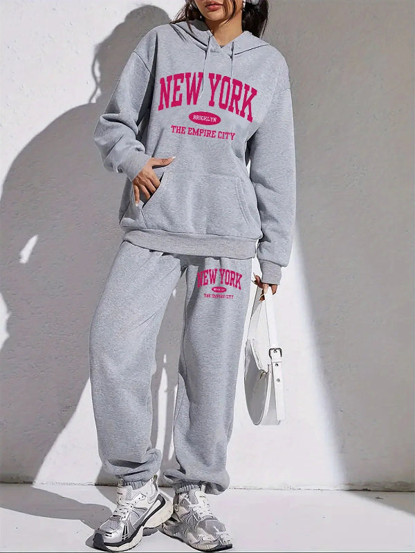 Person wearing a gray 'New York' hoodie and sweatpants with pink text against a white background