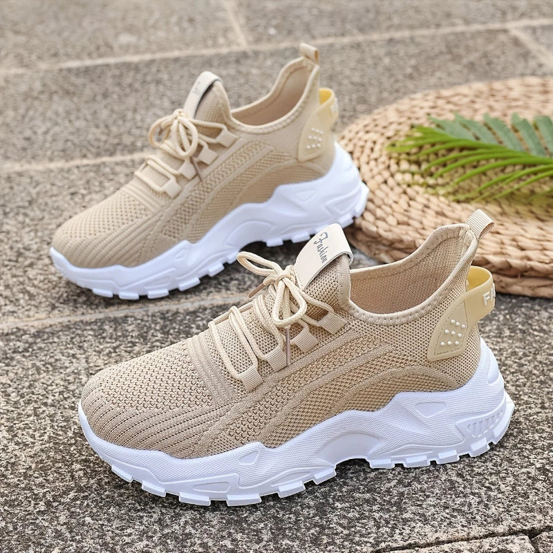 Beige running shoes with white soles on a stone surface