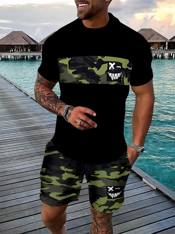 Man wearing a black t-shirt with camouflage design and matching shorts by a waterfront.