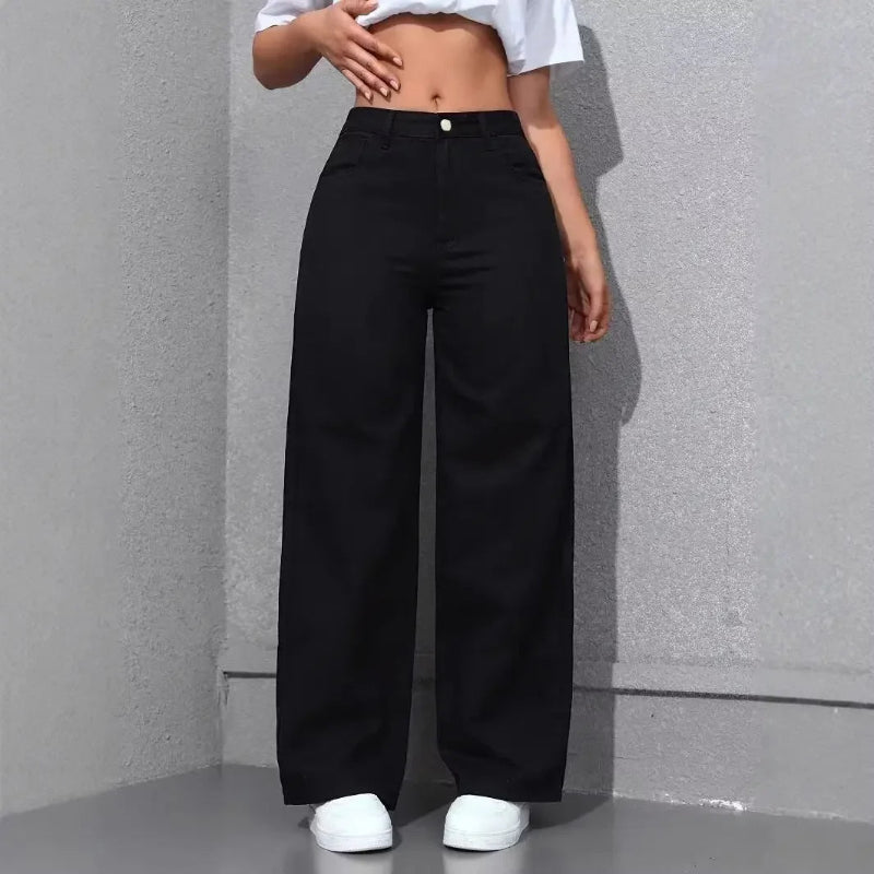 Person wearing black wide-leg pants and a white crop top against a gray wall.