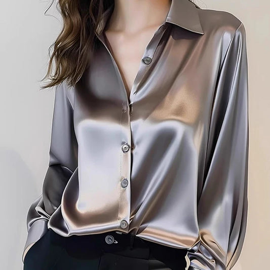 Silky silver blouse worn by a person on a plain background