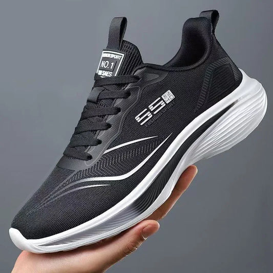 Black running shoe with white sole held in a hand against a gray background