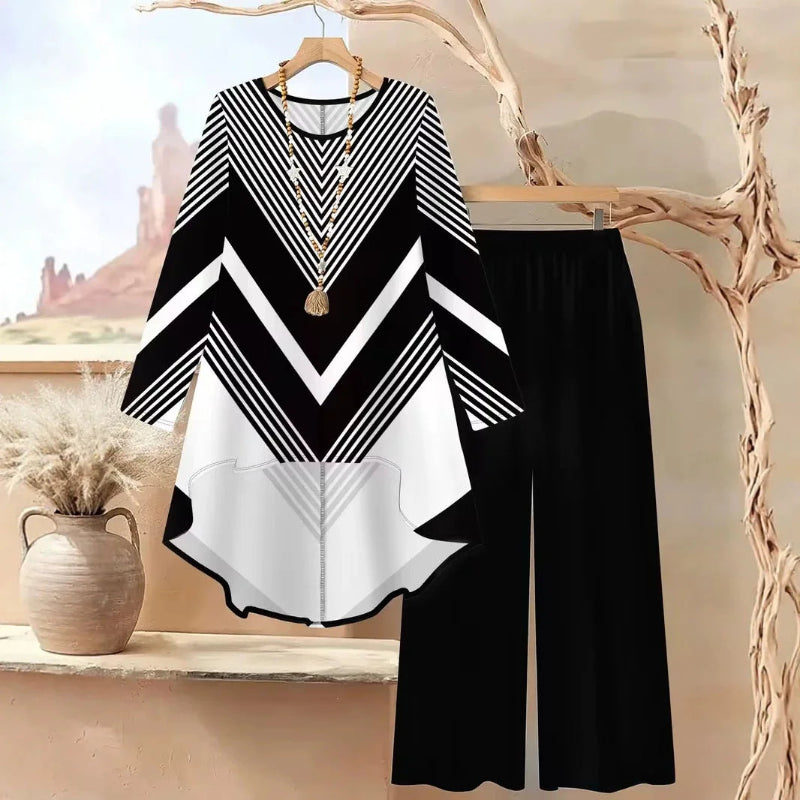 Black and white patterned top with wide-leg pants on a hanger against a scenic background.