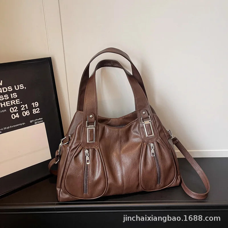Brown leather handbag on a dark surface with a light background